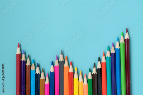 Colored pencils on a turquoise background. View from above. Stationery template. School, office supplies. Creation. Painting.