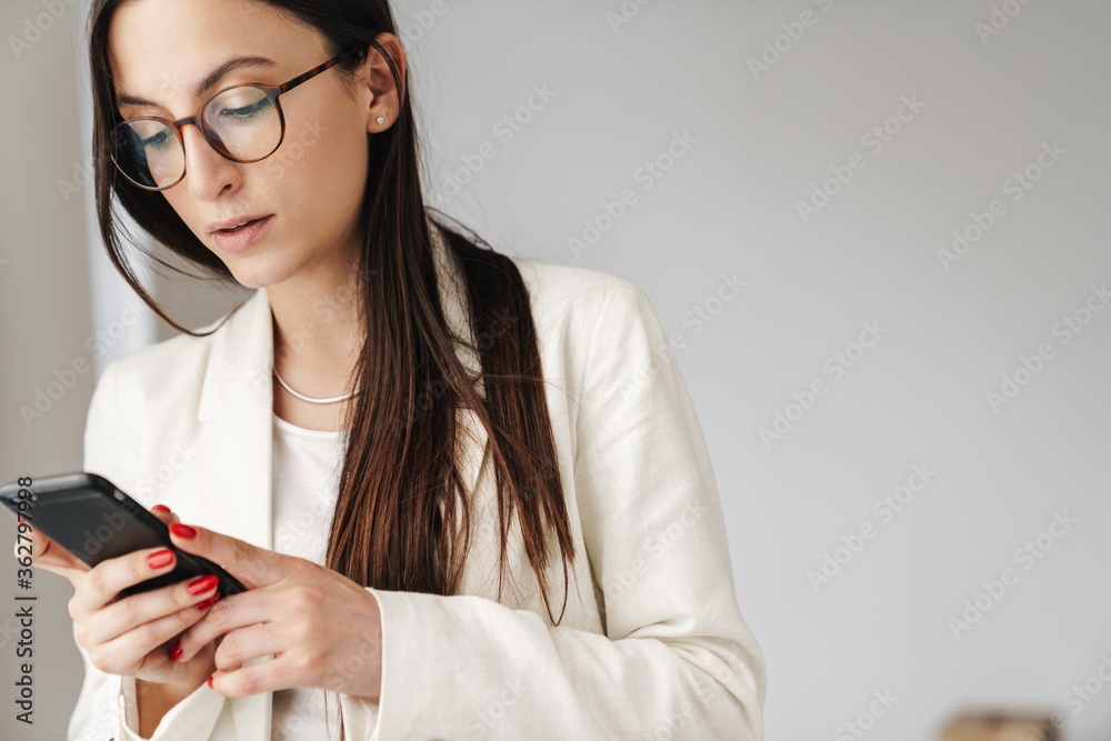 Photo of concentrated businesswoman in eyeglasses using mobile phone