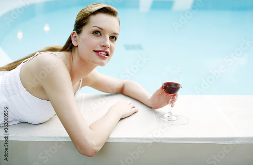 Woman relaxing by the pool side drinking red wine