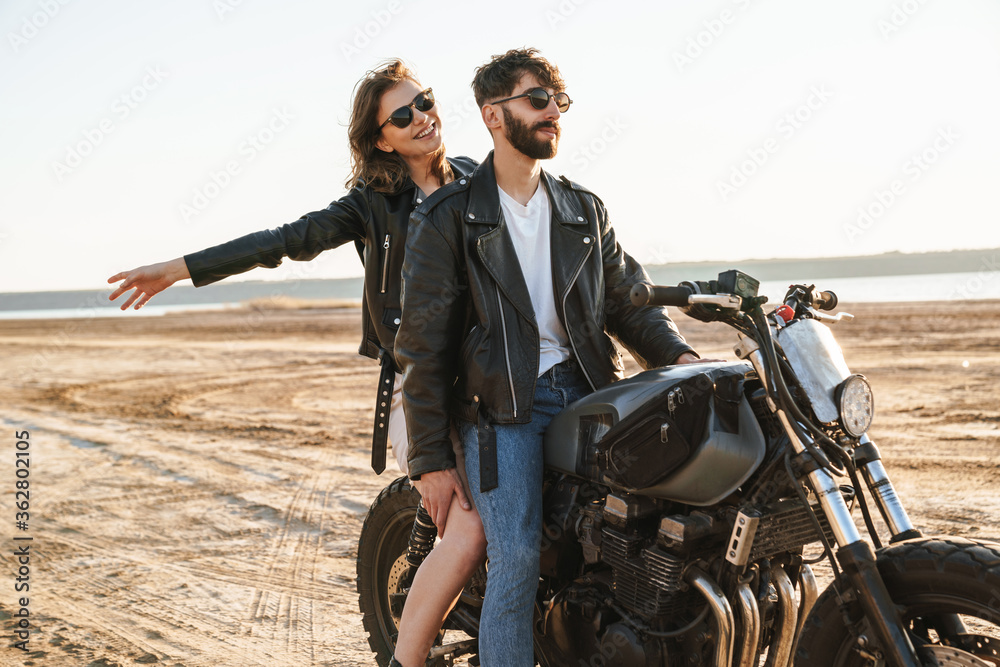 Beatiful yong couple wearing jackets sitting on a motorbike