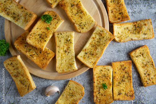 Wooden cutting board with delicious homemade garlic bread on the cement floor