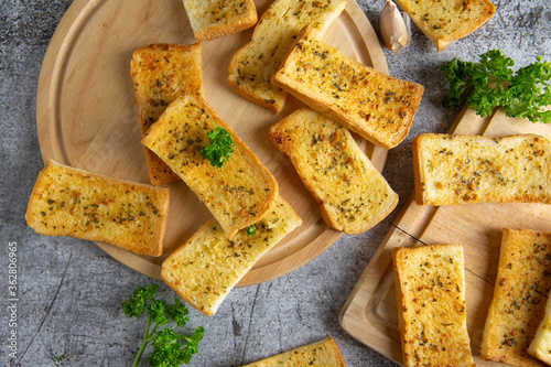 Wooden cutting board with delicious homemade garlic bread on the cement floor