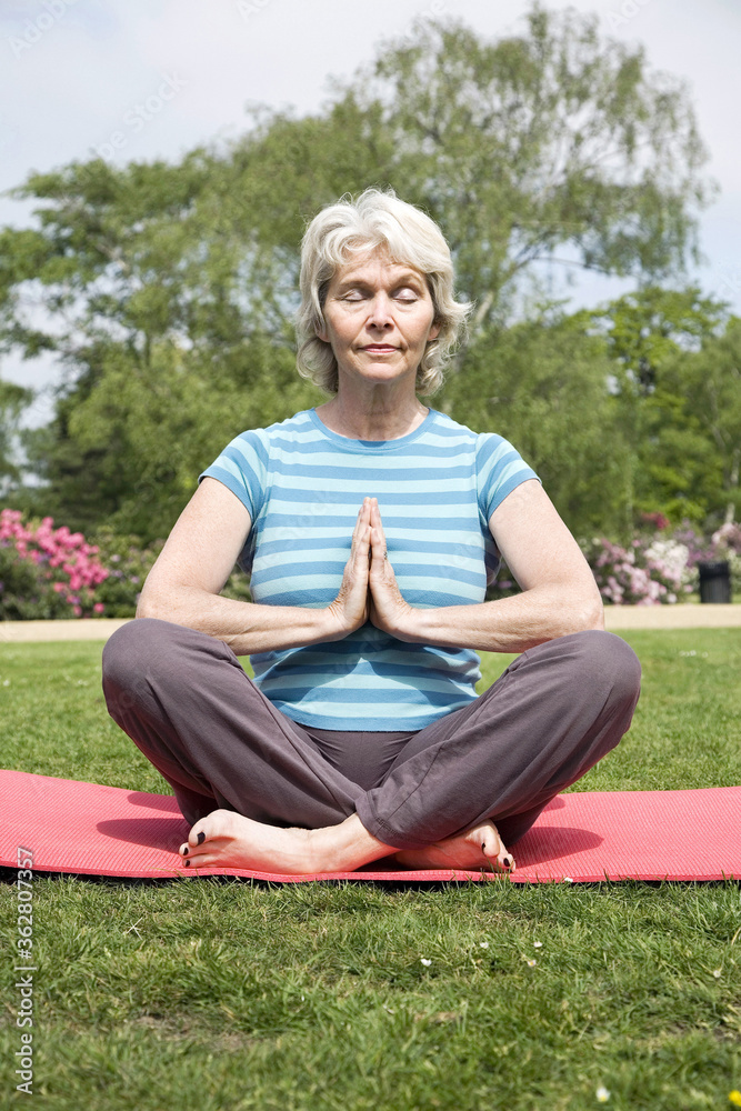 Senior woman with legs crossed, practising yoga Senior woman with legs crossed, practising yoga