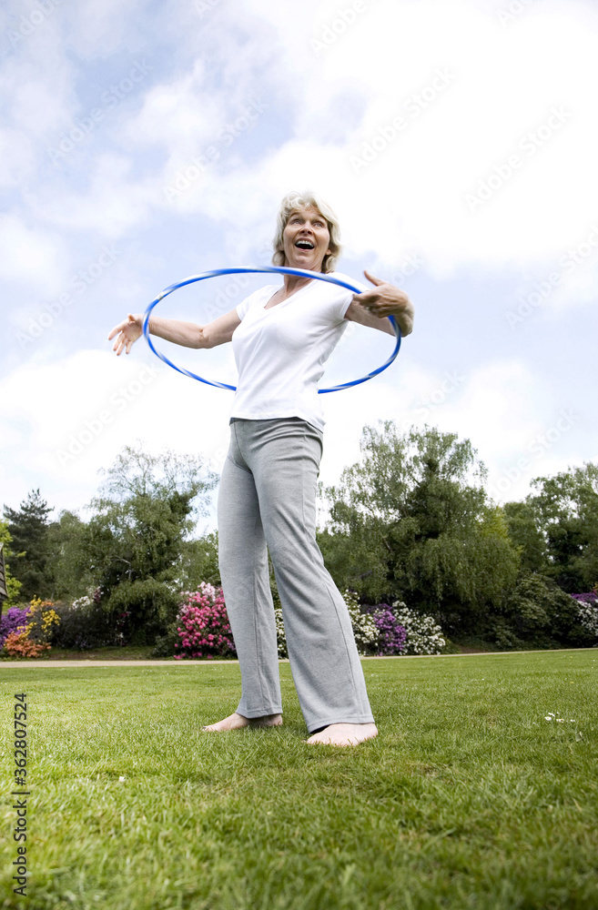 Senior woman playing with plastic hoop in the park Senior woman playing with plastic hoop in the park