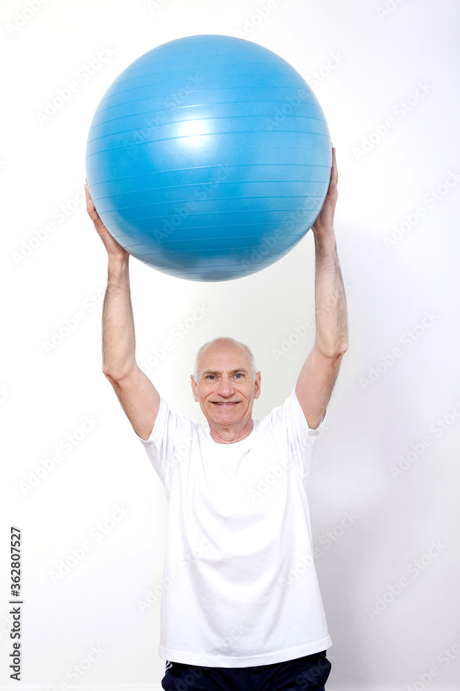 Senior man lifting up gym ball