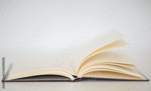 Closeup of a beautiful hardcover notebook with turning empty pages laying flat on a table. Isolated against a white background.