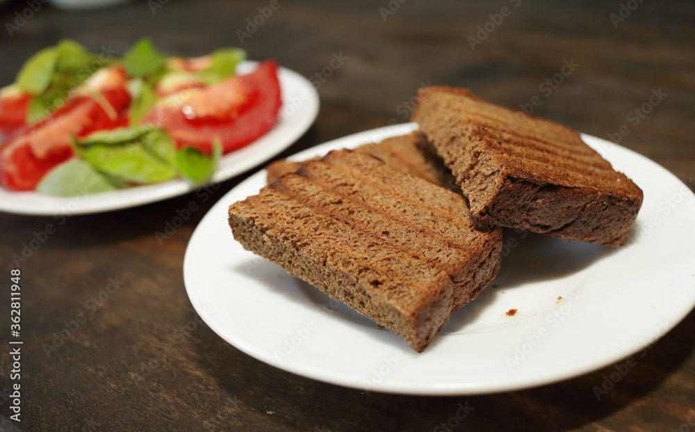 Fresh bread toast. Sliced tomatoes with lettuce on a white plate. Healthy eating concept Fresh bread toast. Sliced tomatoes with lettuce on a white plate. Healthy eating concept