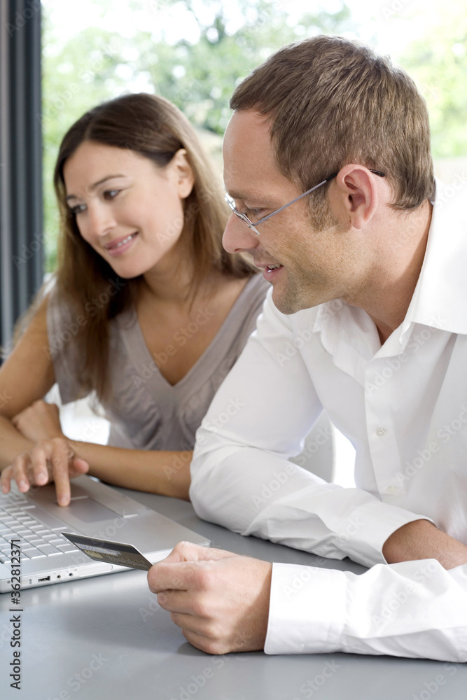 Man and woman using credit card to purchase product online Man and woman using credit card to purchase product online