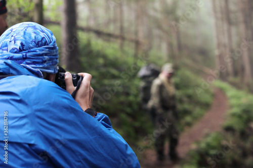 Photographer with camera on tripod shooting a landscape in forest