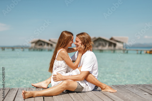 Sensual smiling love couple on a jetty on Maldives enjoy honeymoon on tropical island