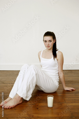 Woman sitting on the floor with a glass of milk beside her