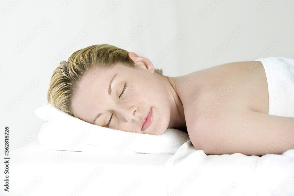 Woman lying forward on massage table with her eyes closed Woman lying forward on massage table with her eyes closed