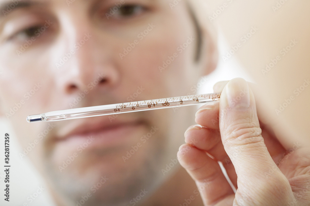 Doctor looking at thermometer in front of patient Doctor looking at thermometer in front of patient