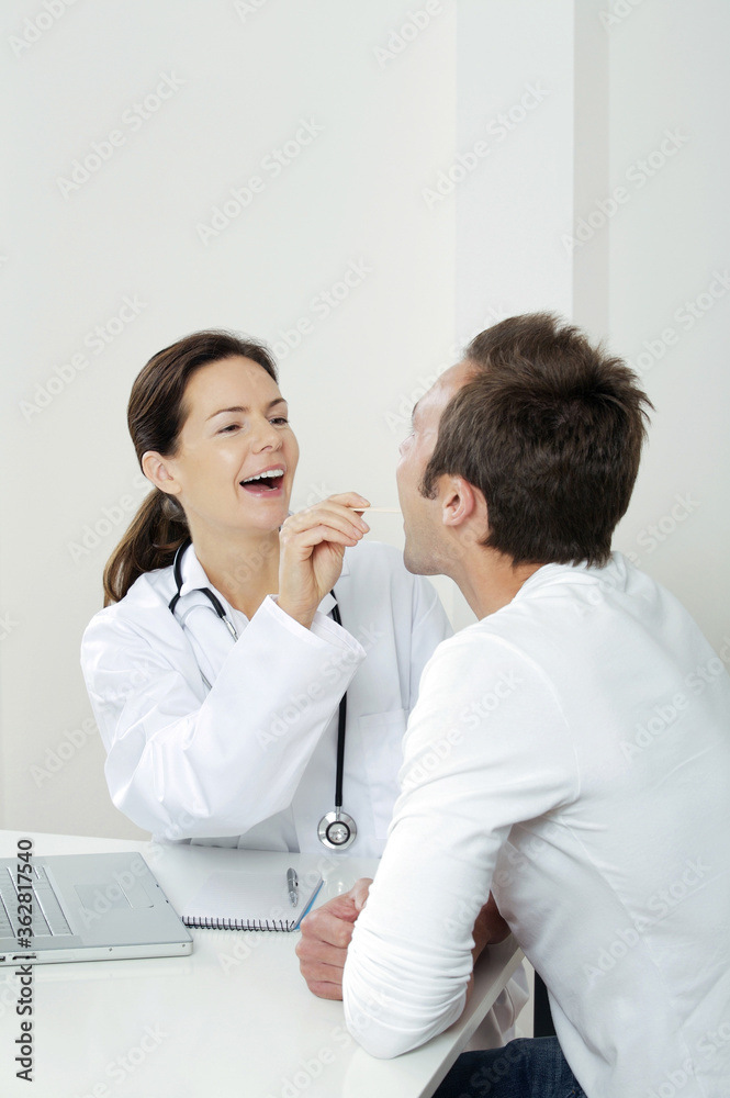 Female doctor using tongue depressor to examine her patient Female doctor using tongue depressor to examine her patient