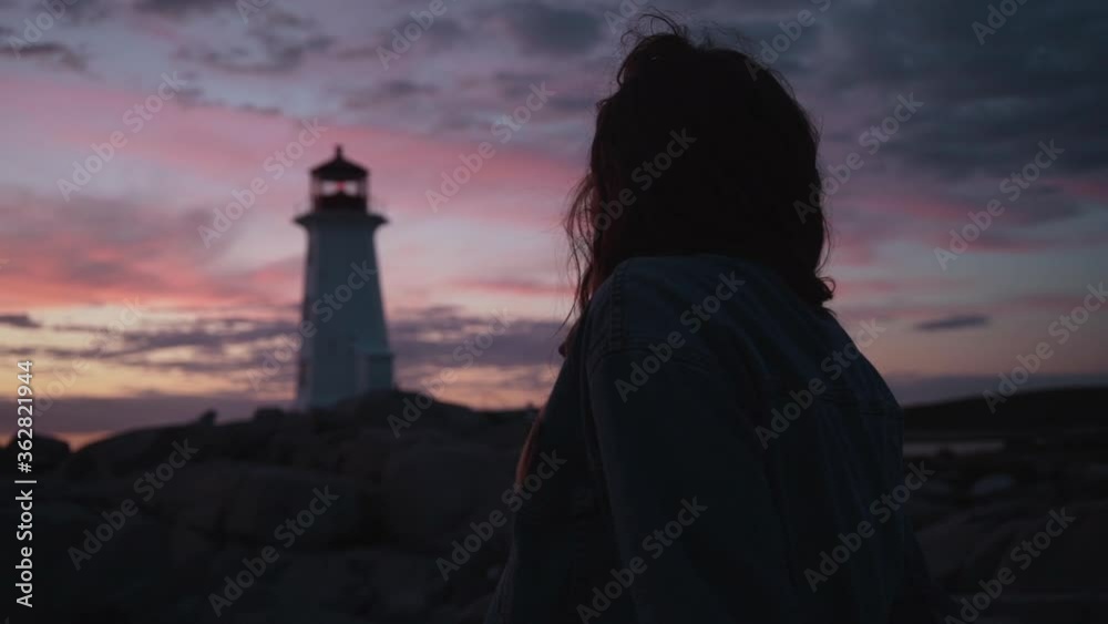 Happy woman against sunset sky and lighthouse