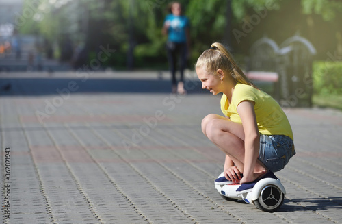 Happy girl child riding a hoverboard in summer park, authentic photo