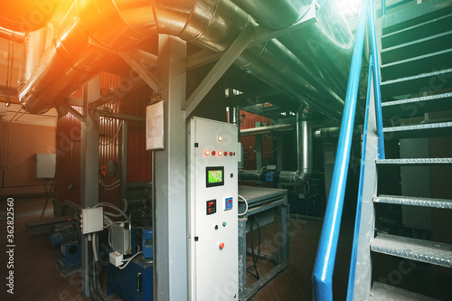 Biomass boilers with control cabinet installed in modern industrial boiler room. Pipe and piple lines for steam supply photo