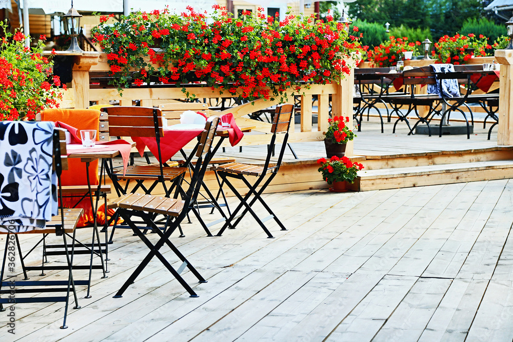 Outdoor cafe. Chairs and tables on the terrace with beautiful flowers at a cozy cafe.