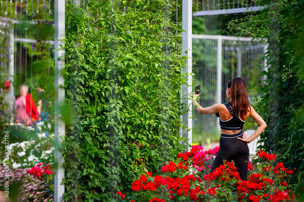 A girl in sportswear takes a selfie in a flower garden A girl in sportswear takes a selfie in a flower garden