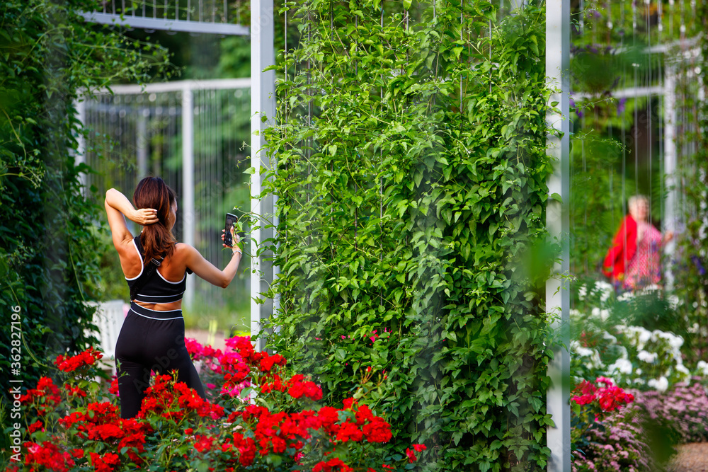 A girl in sportswear takes a selfie in a flower garden A girl in sportswear takes a selfie in a flower garden