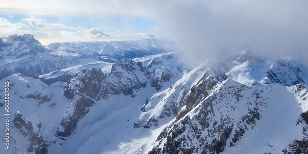 Misty panoramic view of the high mountains covered by clouds in the Dolomites Alps in Italy.