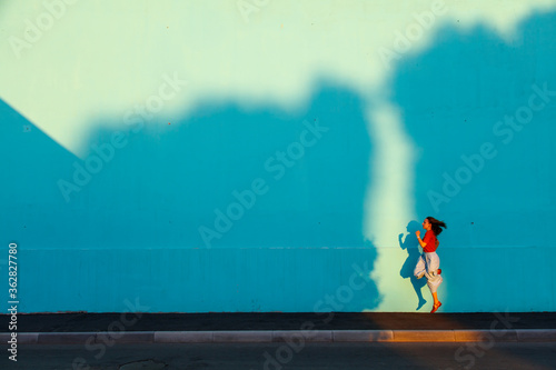Young  woman bouncing. Shadow from sunset on the wall.