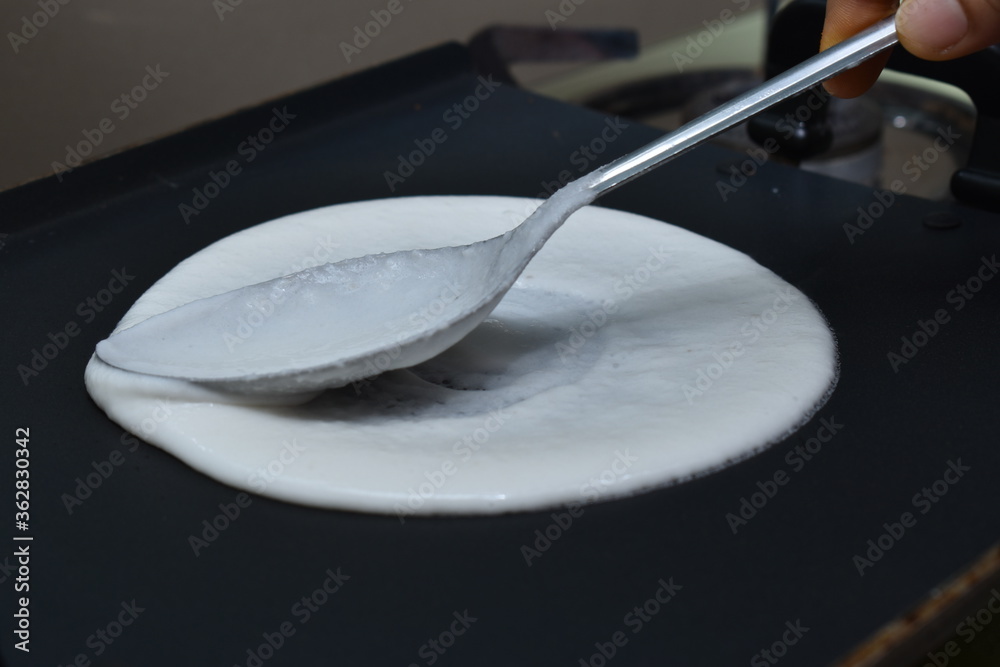 Ταπετσαρία making of round south indian dish(dosa) with white batter and spoon on hot non s
