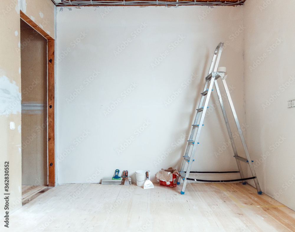 A stepladder with painting tools in a room. Preparing for putty