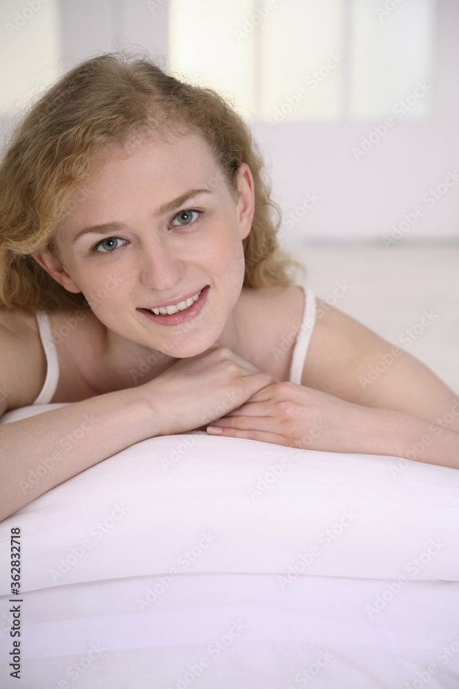 Woman smiling at the camera while lying forward on the bed Woman smiling at the camera while lying forward on the bed