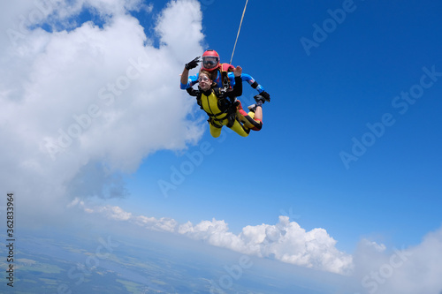 Skydiving. Tandem jump. Happy girl and her instructor are flying in the sky.