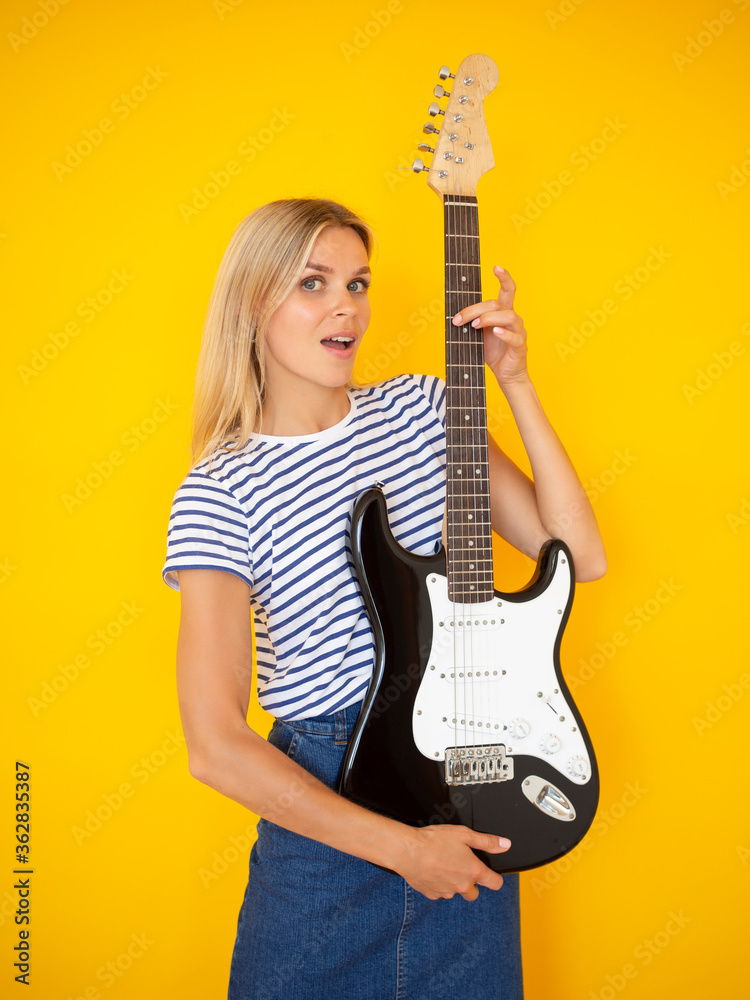 Music band concept. Young woman holds on electric guitar on color background Music band concept. Young woman holds on electric guitar on color background