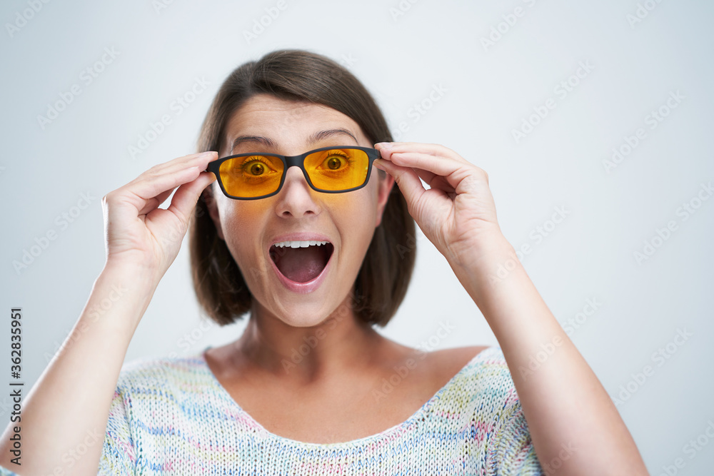 Attractive woman wearing yellow blue blocking glasses isolated over white background Attractive woman wearing yellow blue blocking glasses isolated over white background