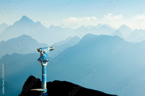 Public binoculars and Mountain Silhouettes at Sunrise. Foresight and vision for new business concepts and creative ideas. Alps, Allgau, Bavaria, Germany. photo