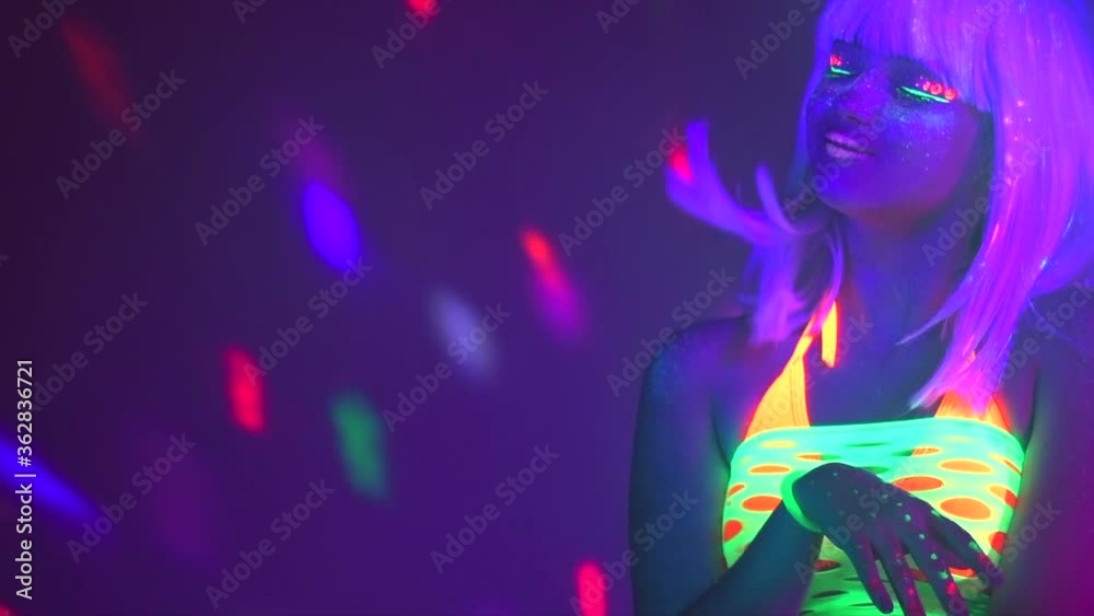 Disco Fashion model dancing woman in neon light, beautiful model girl colorful bright fluorescent make-up, painted skin, Body Art design, disco female in UV, colorful make up. Night club. Slow motion Disco Fashion model dancing woman in neon light, beautiful model girl colorful bright fluorescent make-up, painted skin, Body Art design, disco female in UV, colorful make up. Night club. Slow motion
