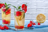 A refreshing summer drink with strawberries, cherries, currants and lemon in glasses on a table
