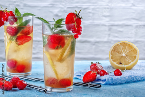 A refreshing summer drink with strawberries, cherries, currants and lemon in glasses on a table