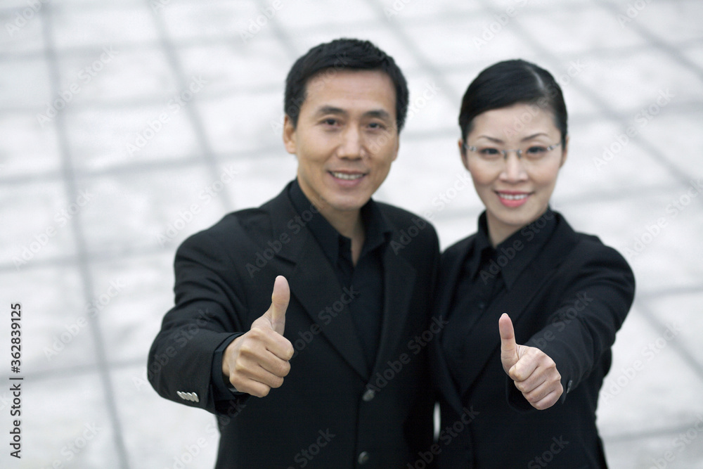 Businessman and businesswoman showing thumbs up