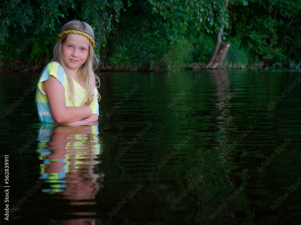 blonde girls with blue eyes bathes in clothes in the dark water of a lake at sunset blonde girls with blue eyes bathes in clothes in the dark water of a lake at sunset