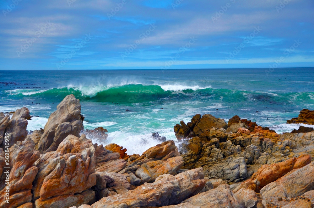 Seascape of beautiful big waves with white foam hitting stone coastline on the sunny windy day, Cape Agulhas, Atlantic ocean, South Africa