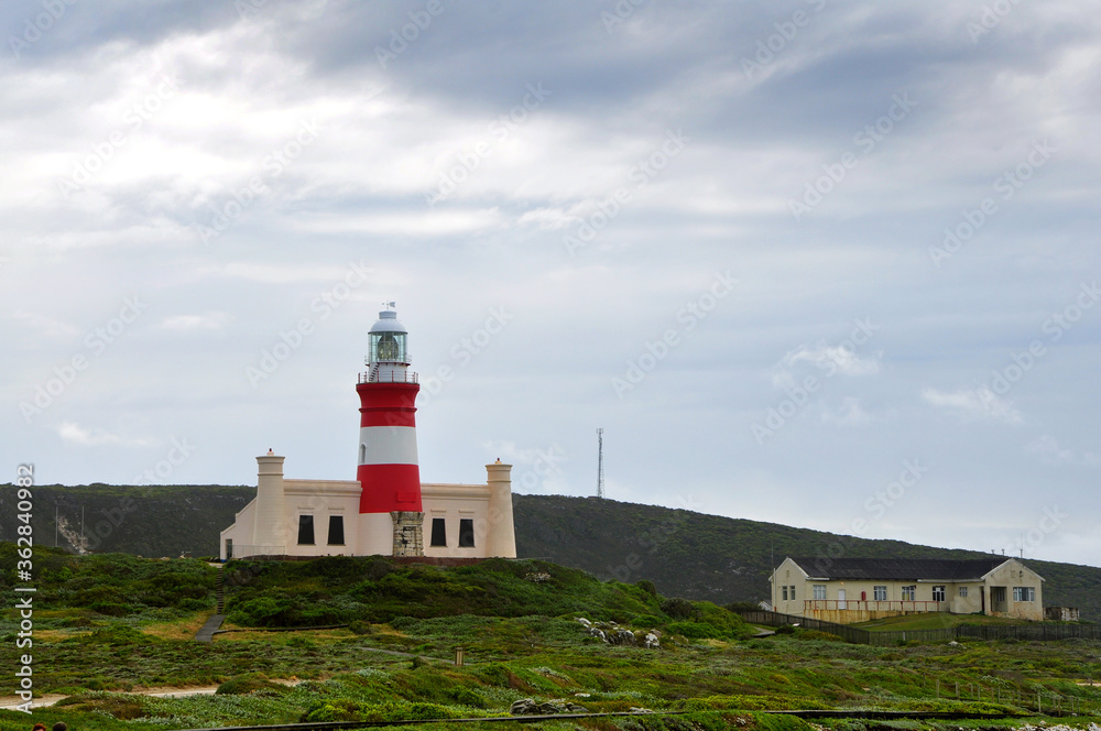 Landscape with the lighthouse on the beautiful rocky cliff on the windy day at Cape Agulhas, the most southern point of Africa, where the Indian and Atlantic oceans meet, South Africa Landscape with the lighthouse on the beautiful rocky cliff on the windy day at Cape Agulhas, the most southern point of Africa, where the Indian and Atlantic oceans meet, South Africa