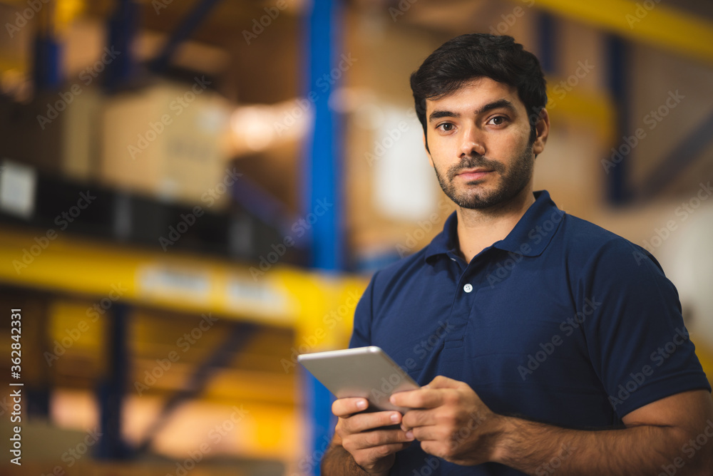 Man warehouse worker using tablet to check and control with modern trade warehouse logistics business, holding digital tablet standing in aisle with goods Man warehouse worker using tablet to check and control with modern trade warehouse logistics business, holding digital tablet standing in aisle with goods