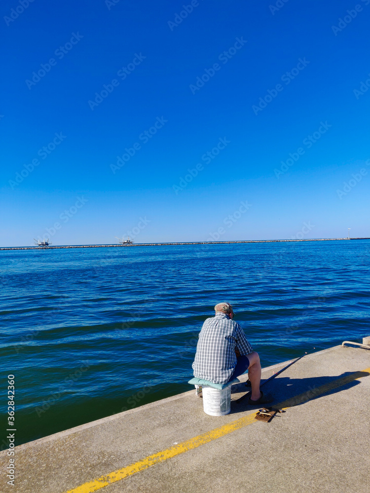 Fisherman on the pier of the port during his fishing