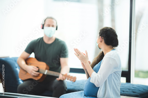 Husband plays guitar for pregnant wife at home