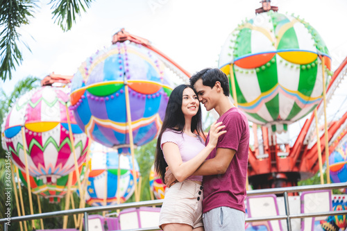 romantic lover couple embracing hug at amusement park, dating at theme park