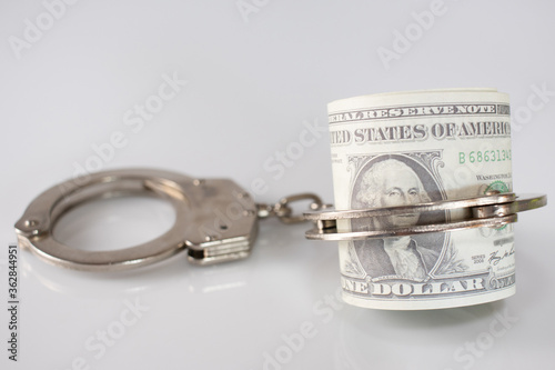 dollars and police handcuffs on a white background