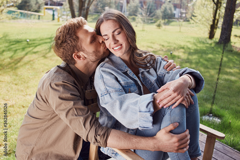 Happy young man kissing her girlfriend outdoors Happy young man kissing her girlfriend outdoors