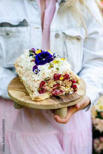 Women's hands holding a tray with a delicious meringue dessert.