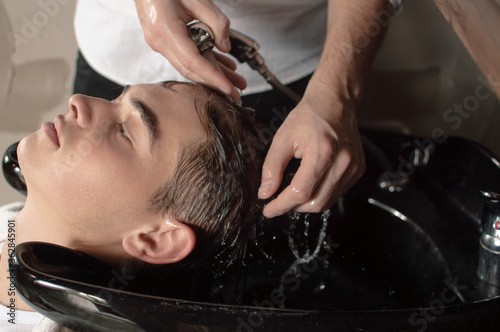 Young man having his hair washed in a hairdressing salon before or after hair cutting.
