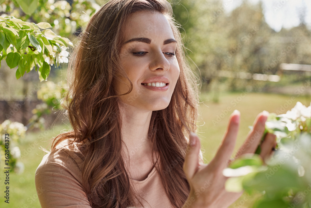 Smiling pretty woman looking at flowering trees Smiling pretty woman looking at flowering trees