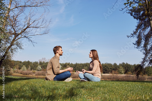 Man and woman meditating with eyes closed outdoors